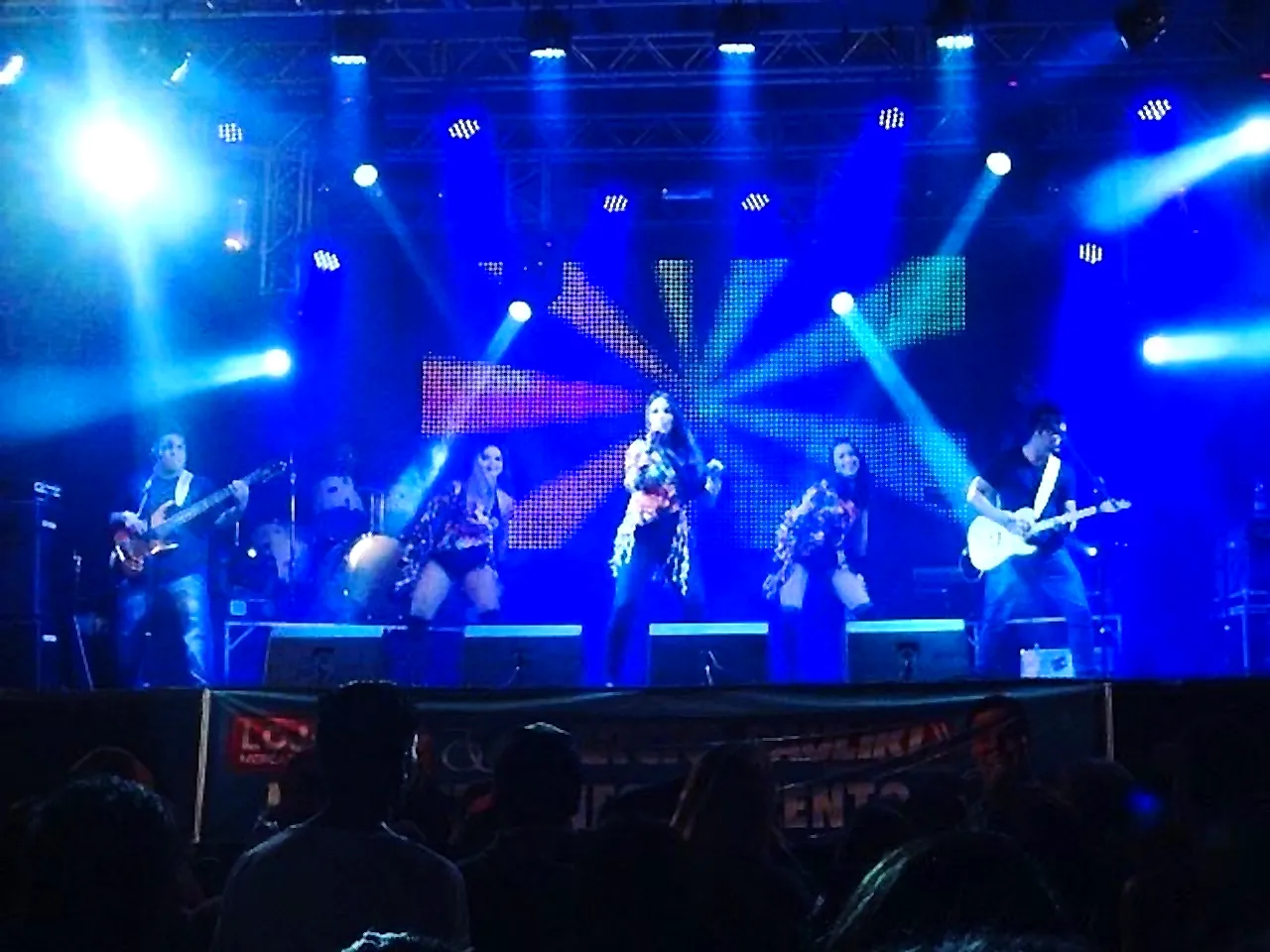 Banda Flor de Menina tocando em palco com telão colorido